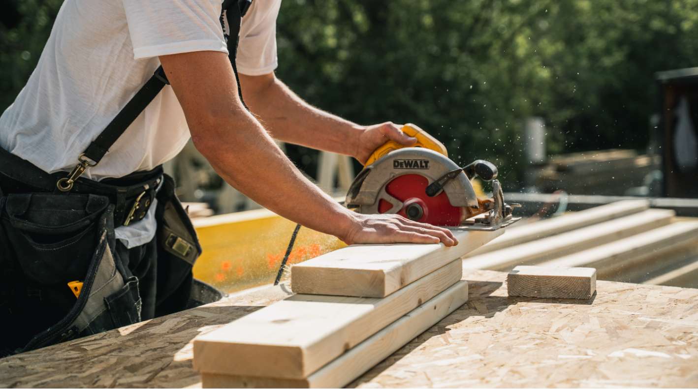 Carpenter sawing lumber for building a house.